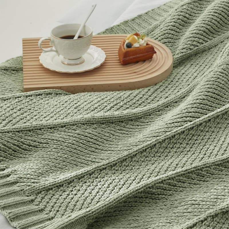 Sage green chunky knit chenille throw blanket styled on a chair for cozy living room decor gallery view 1
