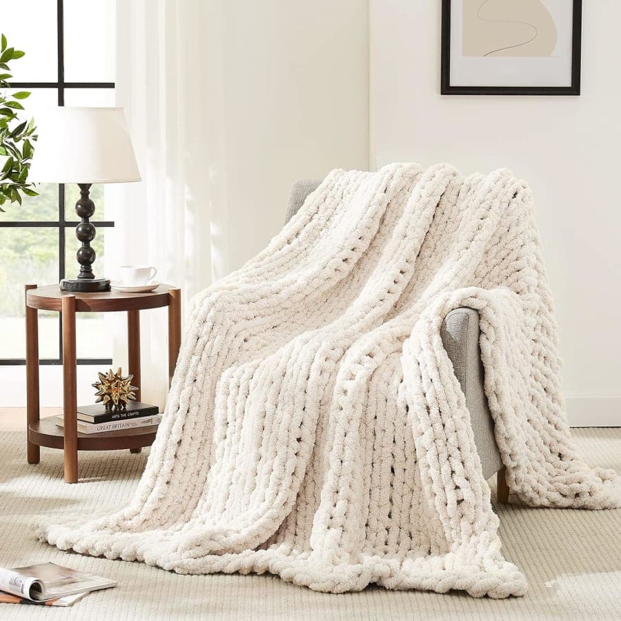 Cream chunky knit chenille throw blanket draped over an armchair for cozy living room decor
