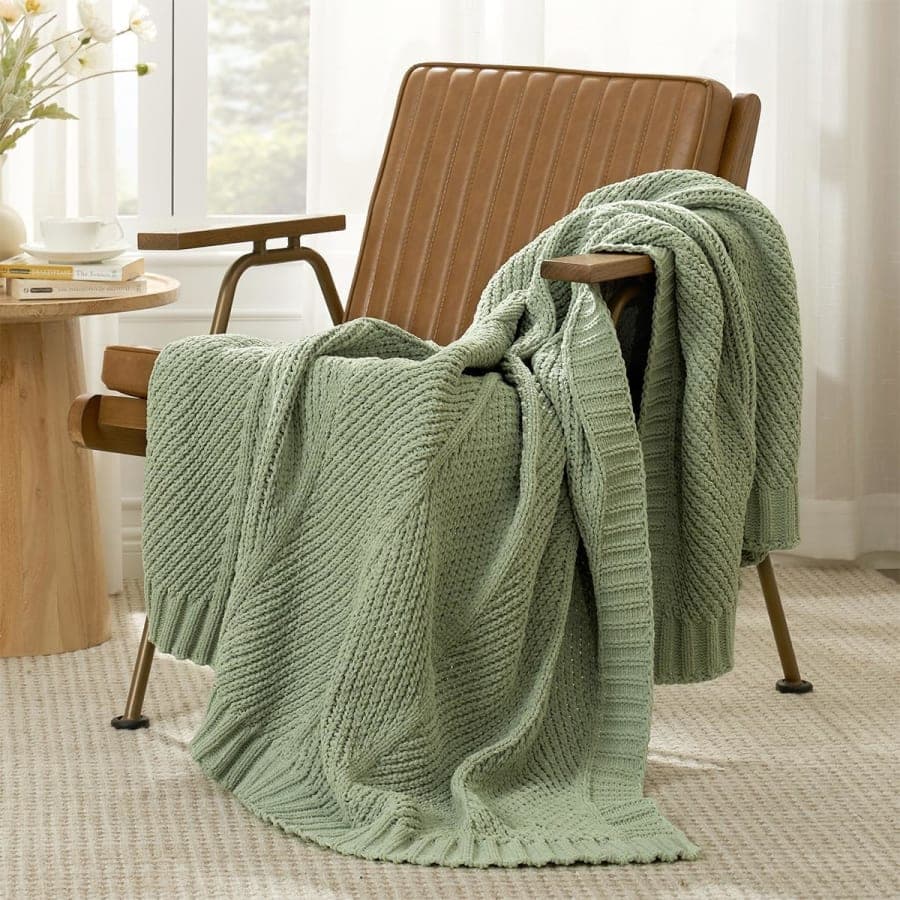 Sage green chunky knit chenille throw blanket styled on a chair for cozy living room decor