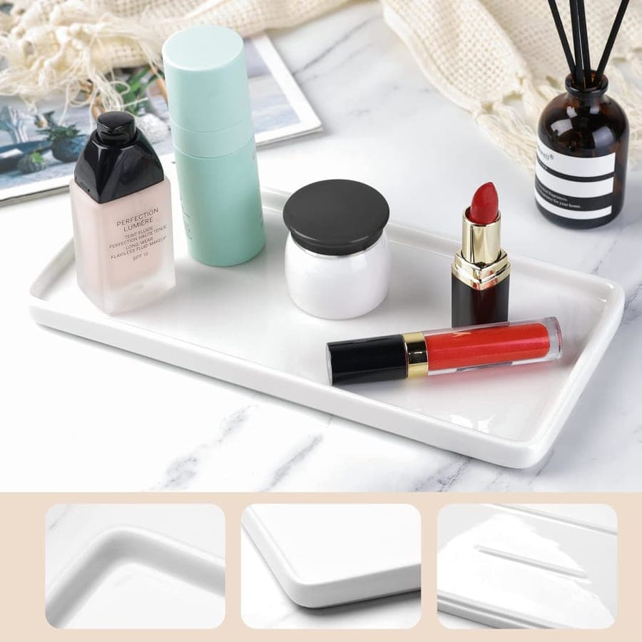 White rectangular ceramic vanity tray holding makeup and skincare products on a marble bathroom counter.